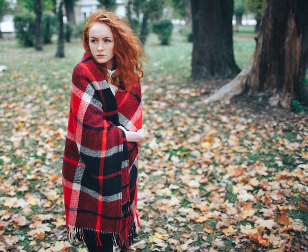 redhead girl on red plaid in autumn park 