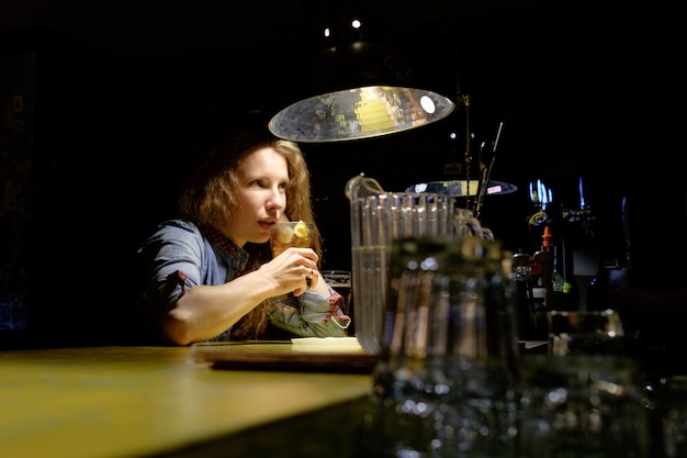 Redhead girl sitting in bar drinking icy cocktail alone