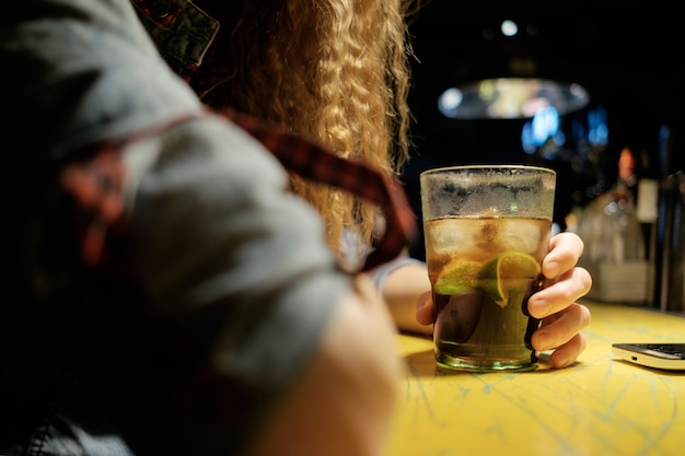 Redhead girl sitting in bar (pub) drinking icy cocktail