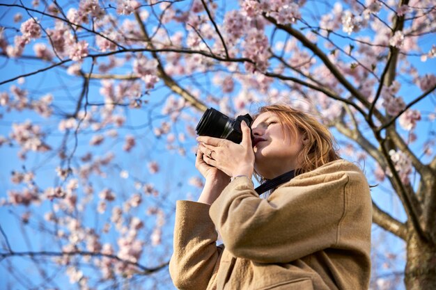 写真 桜の前で写真を撮る赤毛の女の子