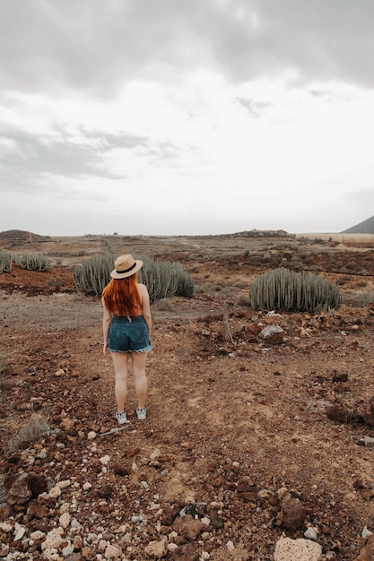 Redhead girl walking through a desert with cacti