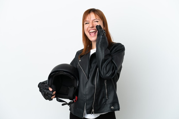 Redhead girl with a motorcycle helmet isolated on white background shouting with mouth wide open