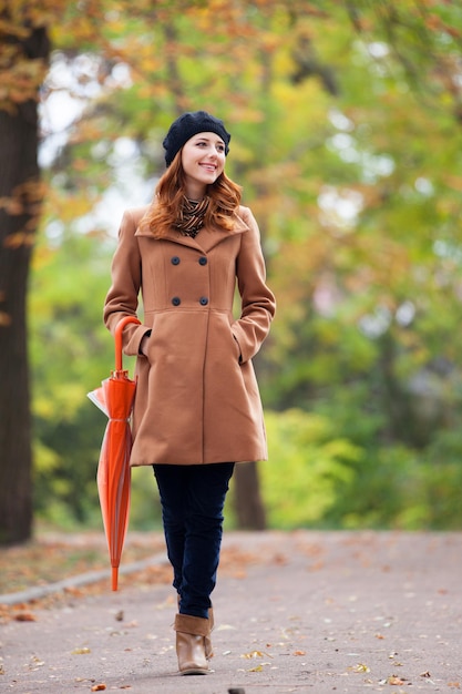 写真 秋の屋外で傘を持つ赤毛の女の子