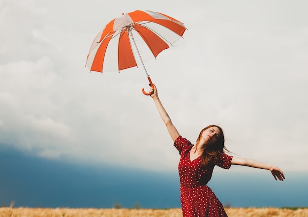 Redhead girl with umbrella at field