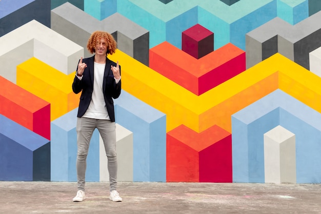 Redhead guy standing near colorful wall