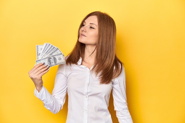 Redhead holding dollar bills finance and wealth concept