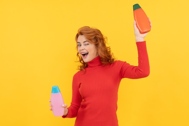 Рыжая дама представляет косметический продукт счастливая женщина использует гель для душа забавная девушка вьющиеся волосы выбирает бутылку шампуня кондиционер для волос реклама косметический продукт ежедневные привычки и уход за собой