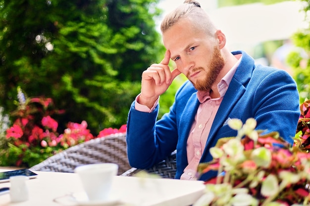 Redhead male using a smartphone in a cafe on a street