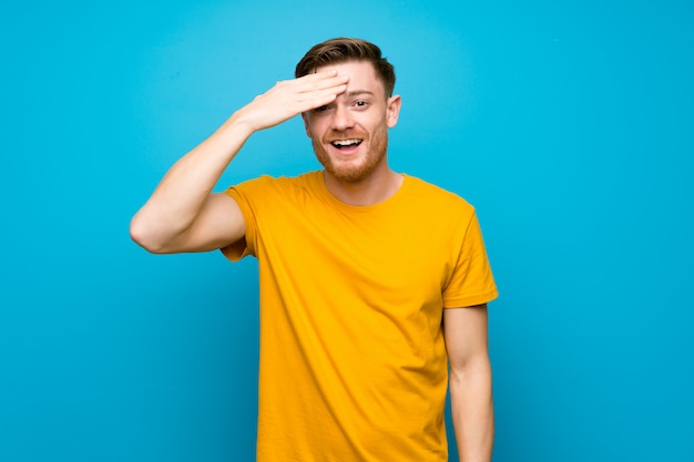 Redhead man over blue wall has just realized something and has intending the solution