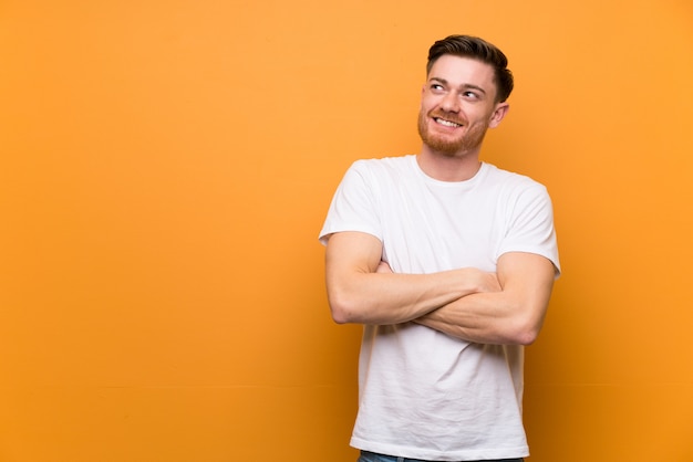 Redhead man brown wall looking up while smiling