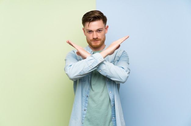 Redhead man over colorful  making NO gesture