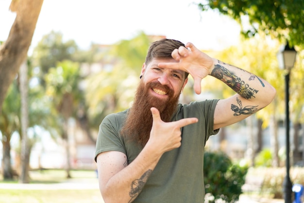 Redhead man with beard focusing face Framing symbol