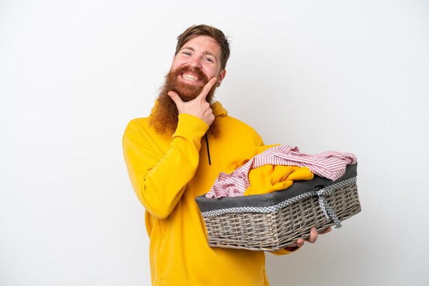 Redhead man with beard holding a clothes basket isolated on white background happy and smiling
