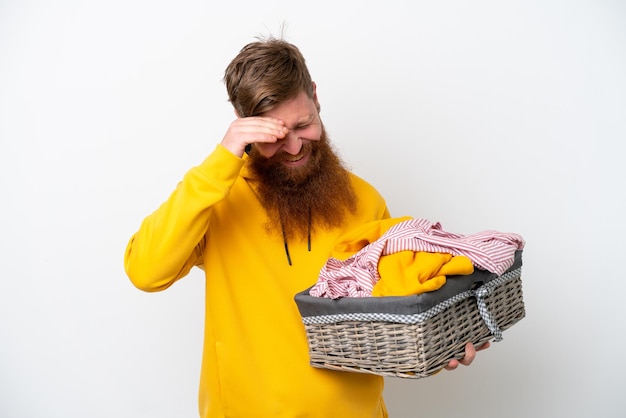 Redhead man with beard holding a clothes basket isolated on white background laughing