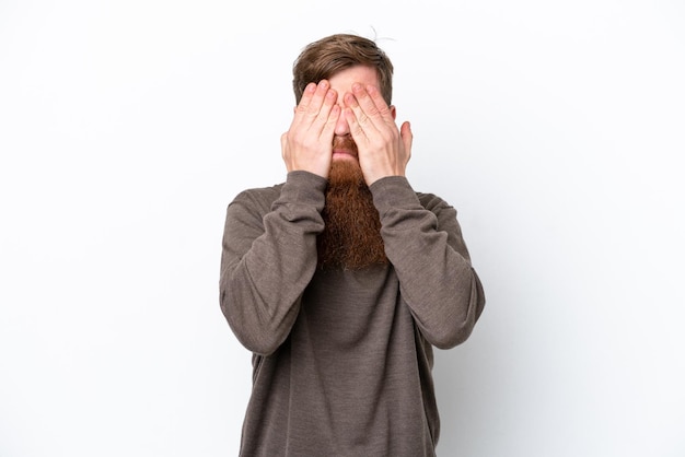 Redhead man with beard isolated on white background covering eyes by hands