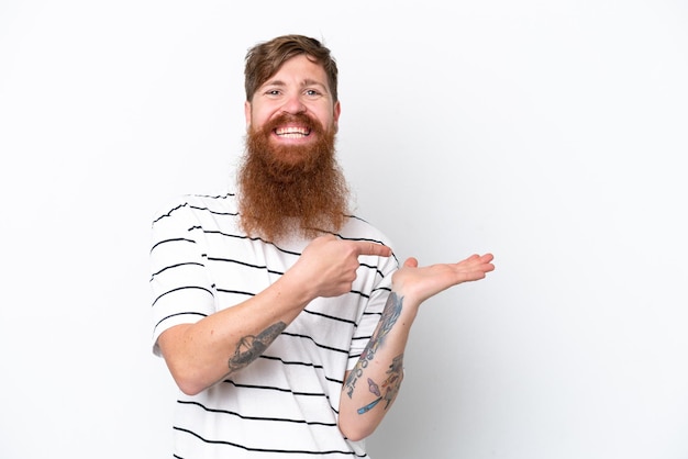 Redhead man with beard isolated on white background holding copyspace imaginary on the palm to insert an ad