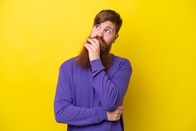 Foto uomo rosso con barba isolato su sfondo giallo con dubbi e con espressione facciale confusa