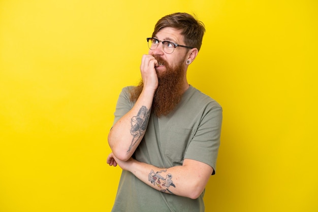 Redhead man with beard isolated on yellow background is a little bit nervous