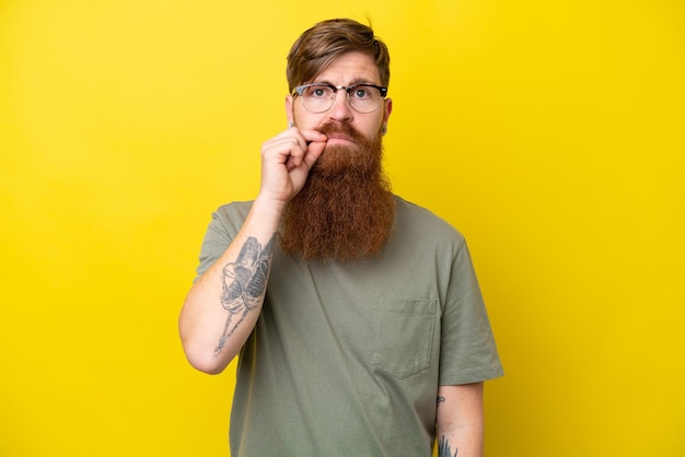 Redhead man with beard isolated on yellow background showing a sign of silence gesture