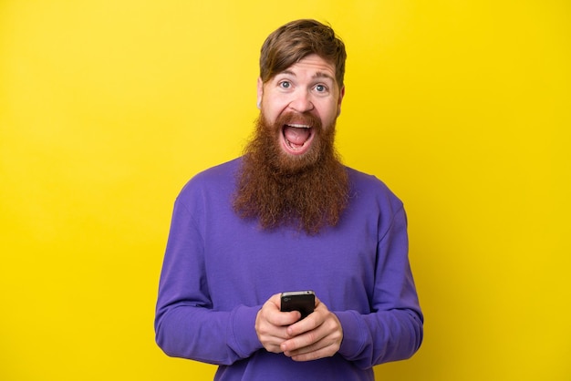 Рыжий мужчина с бородой на желтом фоне удивлен и отправляет сообщение