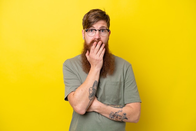 Redhead man with beard isolated on yellow background surprised and shocked while looking right