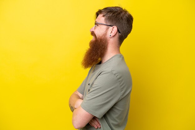 Redhead man with beard isolated on yellow background w in lateral position