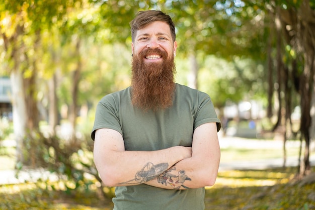 Redhead man with beard keeping the arms crossed in frontal position