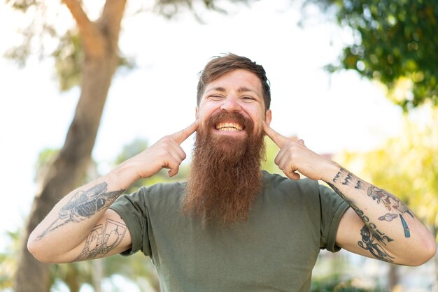 Redhead man with beard smiling with a happy and pleasant expression