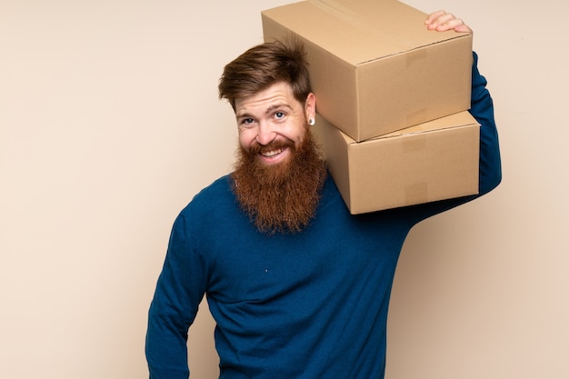 Redhead man with long beard holding a box to move it to another site