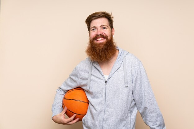 バスケットボールのボールで孤立した背景の上の長いひげを持つ赤毛の男
