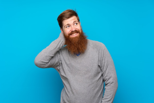 Redhead man with long beard over isolated blue thinking an idea