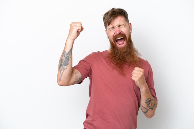 Uomo rosso con barba lunga isolato su sfondo bianco che celebra una vittoria