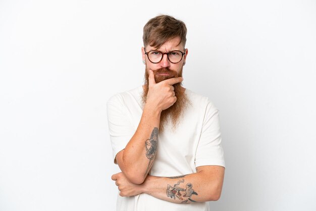 Redhead man with long beard isolated on white background having doubts