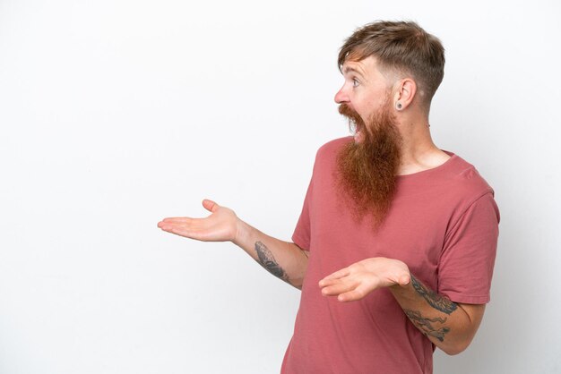 Redhead man with long beard isolated on white background with surprise expression while looking side