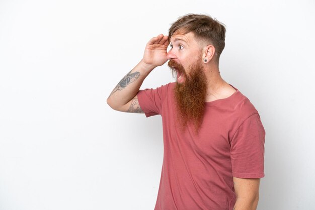 Photo redhead man with long beard isolated on white background with surprise expression while looking side