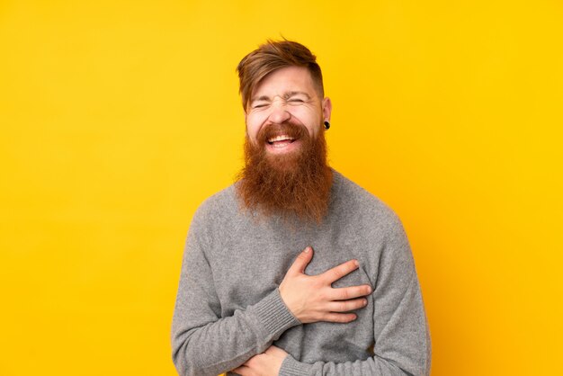 Redhead man with long beard over isolated yellow wall smiling a lot