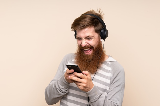 Redhead man with long beard using the mobile with headphones and singing