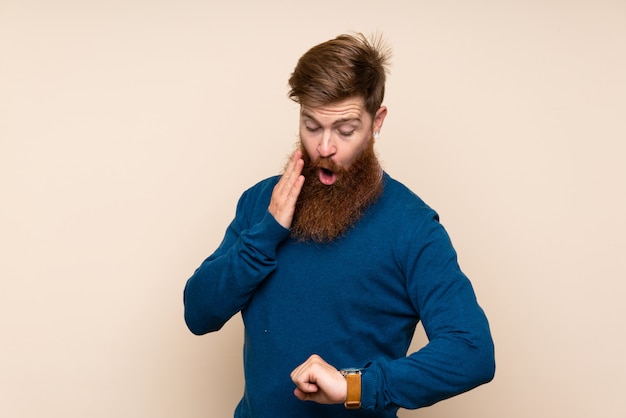 Redhead uomo con la barba lunga con orologio da polso e sorpreso