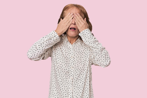 Redhead midaged Caucasian woman in studio afraid covering eyes with hands