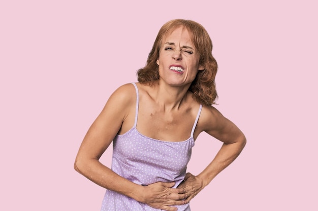 Photo redhead midaged caucasian woman in studio having a liver pain stomach ache