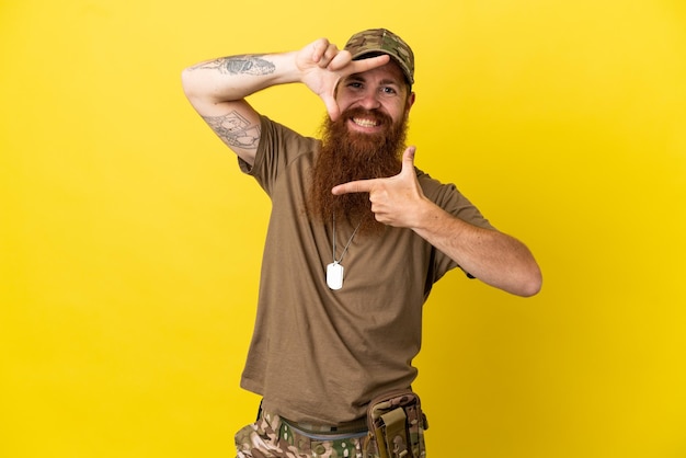 Redhead Militaire man met dog tag geïsoleerd op gele achtergrond gericht gezicht. Frame symbool