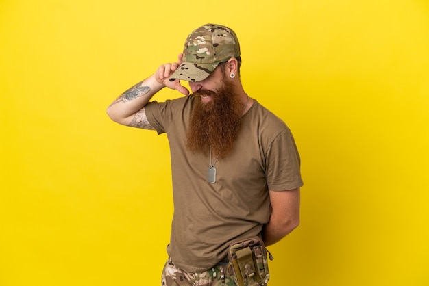 Redhead Military man with dog tag isolated on yellow background laughing