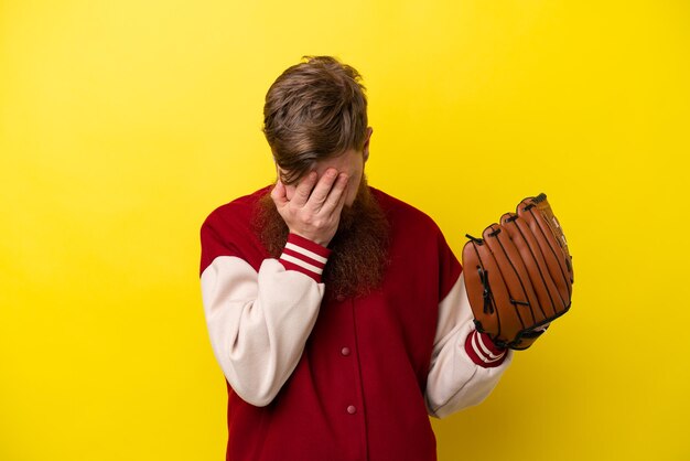 Redhead player man with beard with baseball glove isolated on yellow background with tired and sick expression