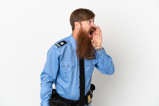 Redhead police man isolated on white background shouting with mouth wide open to the lateral
