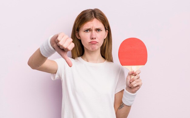 Redhead pretty girl feeling crossshowing thumbs down ping pong concept