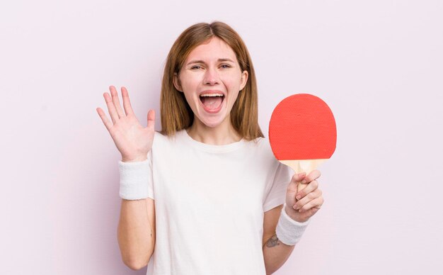 Redhead pretty girl feeling happy and astonished at something unbelievable ping pong concept