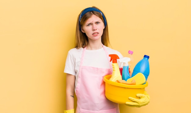 Redhead pretty girl feeling puzzled and confused housekeeper concept