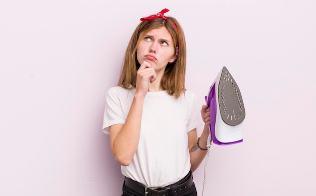 Redhead pretty girl thinking feeling doubtful and confused housekeeper concept