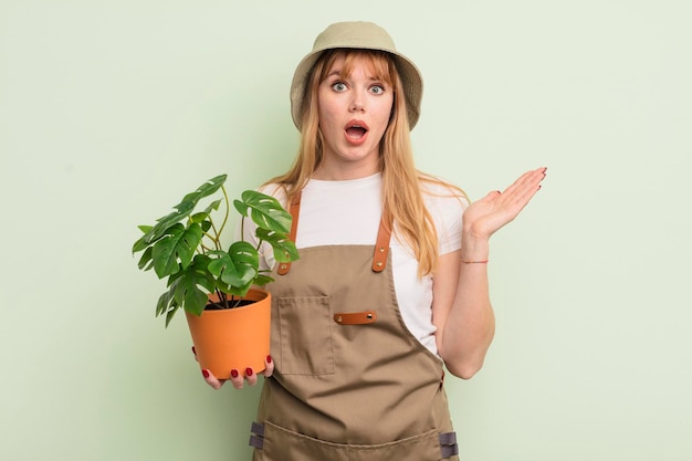 Donna graziosa rossa che si sente felice sorpresa realizzando una soluzione o un concetto di giardiniere di idea