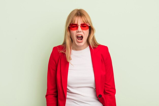 redhead pretty woman shouting aggressively, looking very angry. cool businesswoman concept